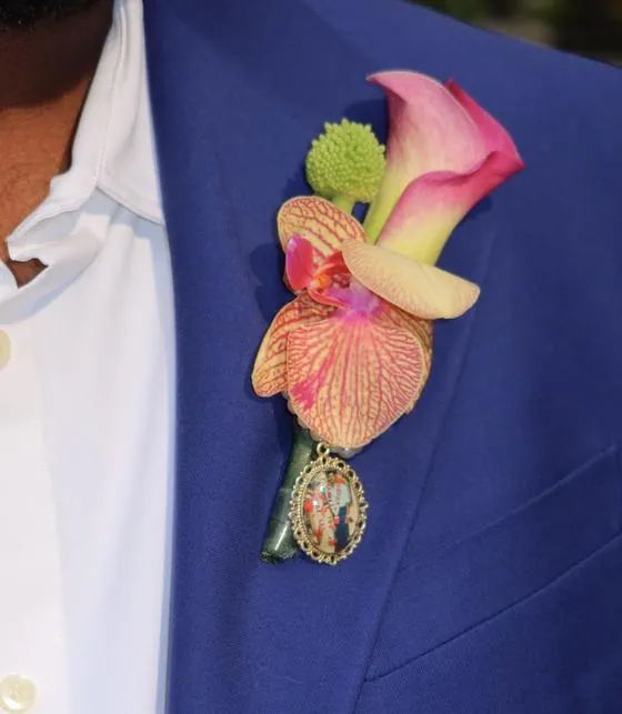 Boutonnière with pink calla lily, orchid, and photo locket on a blue suit