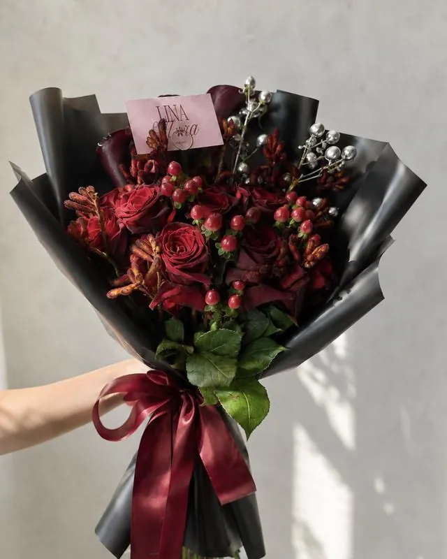 Custom deep red rose bouquet in black wrapping, finished with a burgundy ribbon