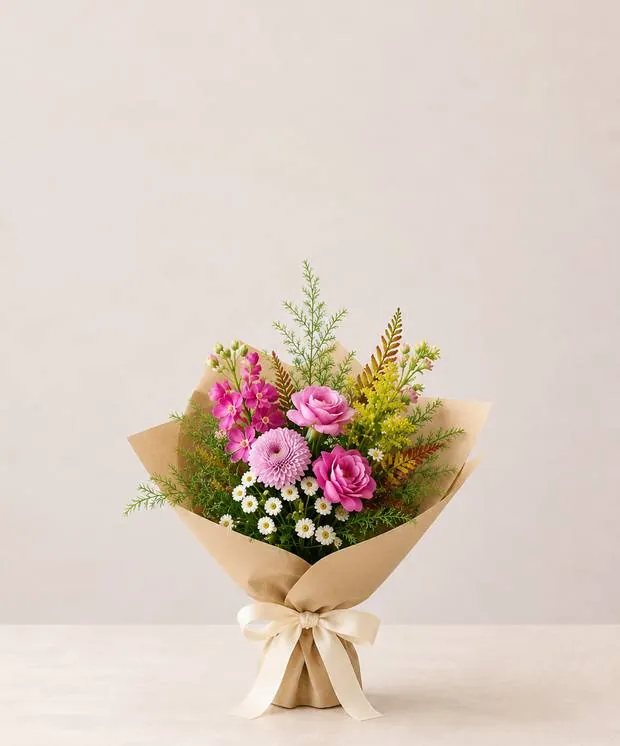 Petite wrapped bouquet of pink roses and daisies in kraft paper